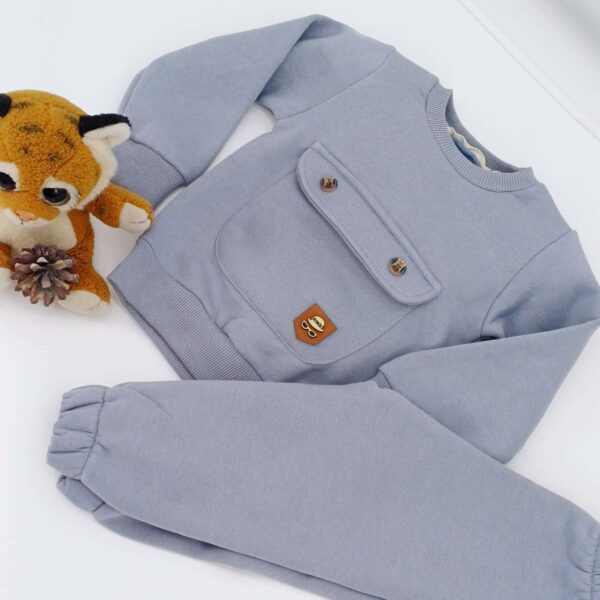 Ensemble hiver bébé gris avec pull et pantalon, doté d'une poche décorative et taille élastique. Disponible en tailles 9-12, 12-18, et 18-24 mois. Parfait pour garder votre enfant au chaud cet hiver.